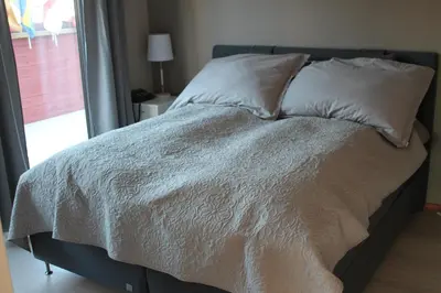 a bed with white sheets and pillows next to a window at Kløver Hotel in Sauda