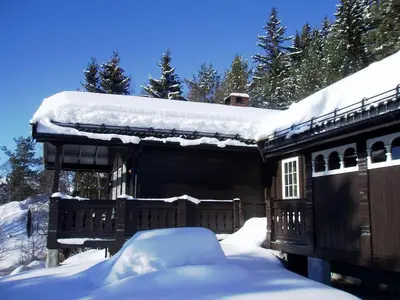 a house covered in snow with snow on the roof at Hogstul Hytter - Knatten - 3 Bedroom Cottage in Tuddal