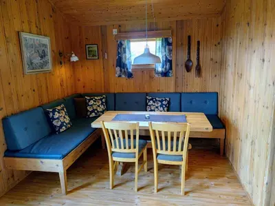 a dining room with a blue couch and a table at Hogstul Hytter - Apartment South in Tuddal