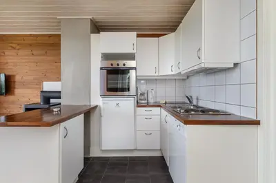 a white kitchen with white appliances and wooden walls at Nordseter Apartments in Lillehammer