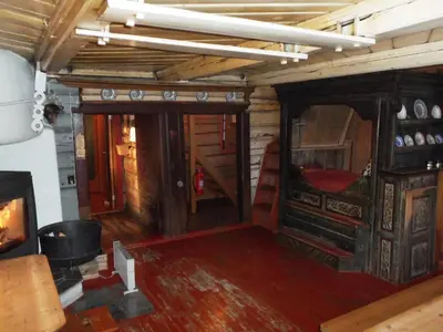 a room with a room with a fireplace and a room with a stove at Hogstul Hytter - Gamlestua in Tuddal