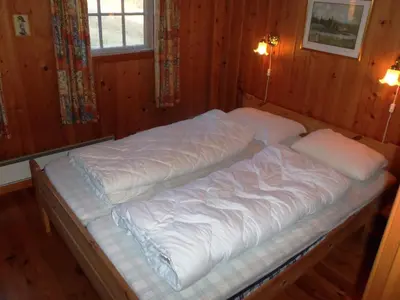 a large bed in a room with wooden walls at Hogstul Hytter - Gamlestua in Tuddal