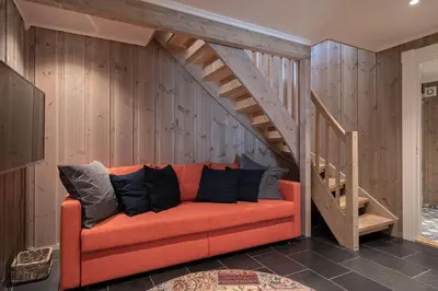 an orange couch in a room with a wooden staircase at Tinden Grendehytte in Beitostøl