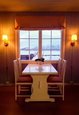 a table and chairs in a room with a window at Storestølen Fjellhotell in Hovet