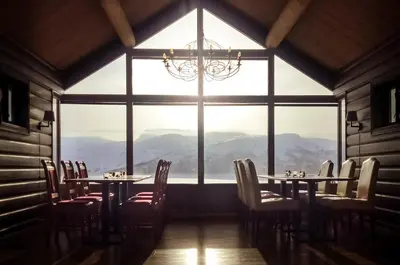 a room with tables and chairs and a large window at Storestølen Fjellhotell in Hovet