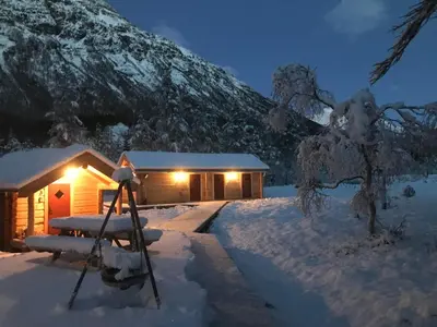 a cabin in the snow with a tripod in front of it at Camp Dronningkrona in Ålvundeid