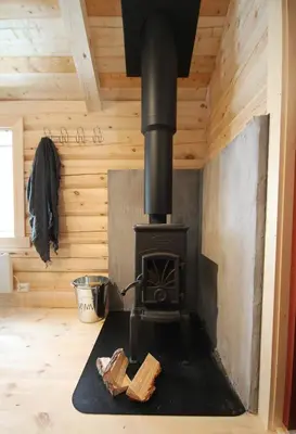 a stove in a room with a wooden ceiling at Camp Dronningkrona in Ålvundeid