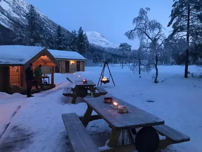 a picnic table in the snow next to a cabin at Camp Dronningkrona in Ålvundeid