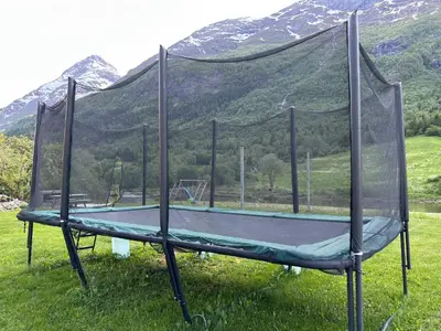 a trampoline in a field with mountains in the background at Naustvoll in Olden