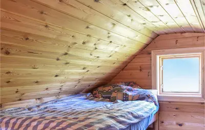 a bed in a room with a wooden wall at Stunning Home In Haulandshella in Tveitevåg