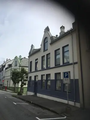 a white and blue building with a parking sign in front of it at Ålesund downtown loft room with shared bathroom in Ålesund