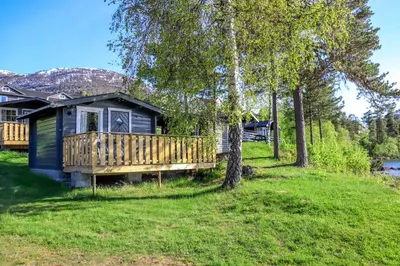 a cabin in the woods with a deck and trees at Lyngmo Hytter in Hafslo