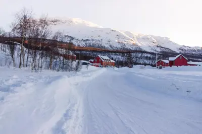 a snow covered road with houses and a mountain at Maristova apartment 110 in Filefjell