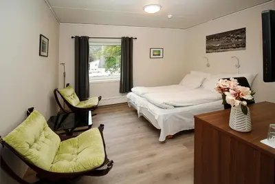 a bedroom with a bed and two chairs and a window at Sentrum Hotel in Nordfjordeid