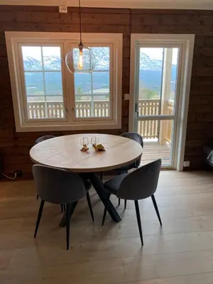 a dining room with a table and chairs and windows at Oppdal Alpintun in Oppdal