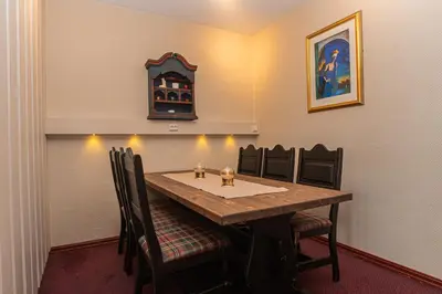 a dining room table with chairs and a clock on the wall at Fanitullen Apartments in Hemsedal