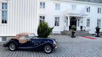 an old blue car parked in front of a white building at Hovde Gård in Brekstad