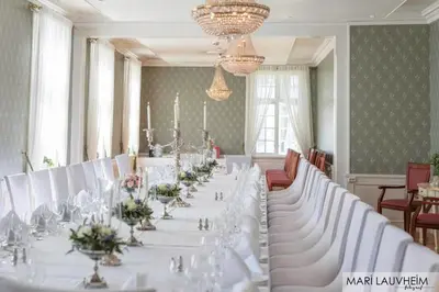 a long dining room with white tables and flowers at Hovde Gård in Brekstad