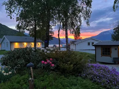 a house with a garden in front of a sunset at Kinsarvik Camping in Kinsarvik