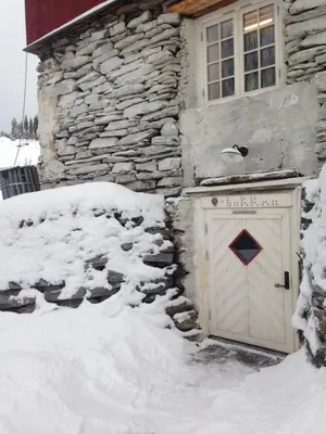 a snow covered garage in front of a stone building at Ivaregga Vinterstua in Tolga