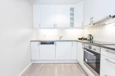 a white kitchen with white cabinets and a sink at Knutholmen in Kalvåg