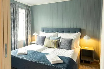 a bedroom with a large bed with blue walls at Knutholmen in Kalvåg