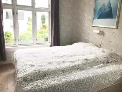 a bed in a bedroom with two windows at Villa Holmen in Balestrand