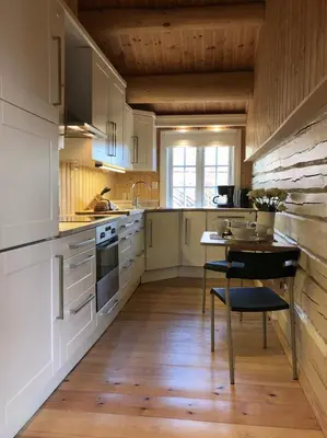 a kitchen with white cabinets and a table with a chair at Svenskveien 23b in Røros