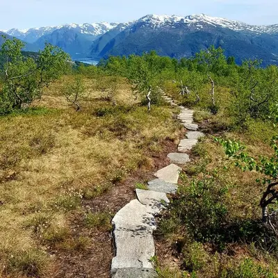 a stone path on a hill with mountains in the background at Villa Holmen 2 in Balestrand
