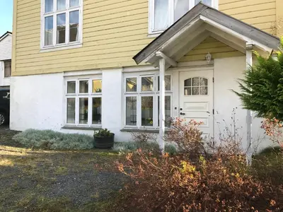 a yellow and white house with a white door at Villa Holmen, ground floor apartment in Balestrand