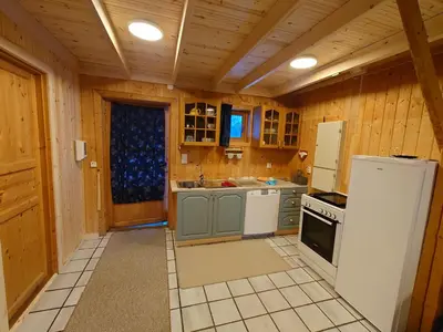 a kitchen with wooden walls and a white refrigerator at Trollbu Aabrekk gard in Briksdalsbre