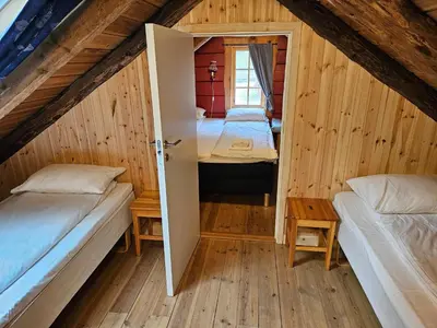 a room with two beds and a window in a attic at Trollbu Aabrekk gard in Briksdalsbre