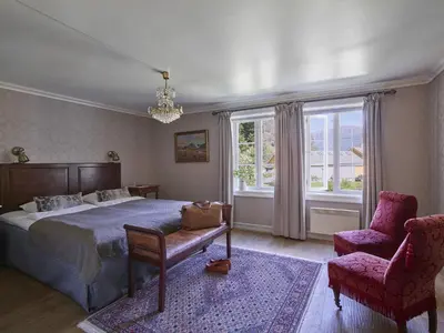 a bedroom with a bed and a chair and a window at Fretheim Hotel in Flåm