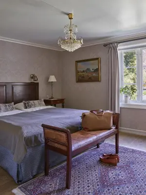 a bedroom with a bed with a bench and a chandelier at Fretheim Hotel in Flåm