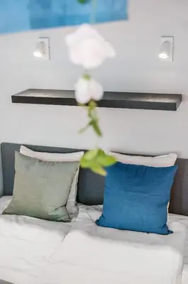 a white flower on top of a bed with pillows at NG Apartments in Bergen
