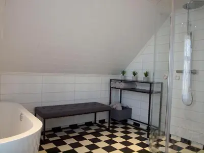 a bathroom with a tub and a bench next to a shower at Kårstua - Austrått Agroturisme in Austrått