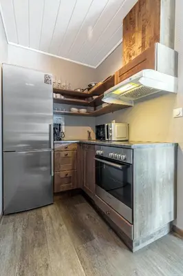 a kitchen with a stainless steel refrigerator and wooden cabinets at Hemsedal Cafe Skiers Lodge in Hemsedal