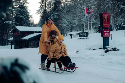 a woman and child on a sled in the snow at Hunderfossen Cottages in Hafjell