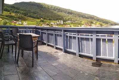 a balcony with chairs and a table and a view of the water at Apartment in Herand, Hardanger in Herand
