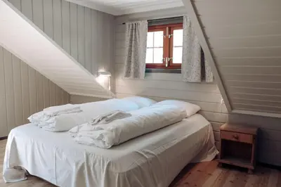 a bed with white sheets in a room at Hunderfossen Apartments in Hafjell