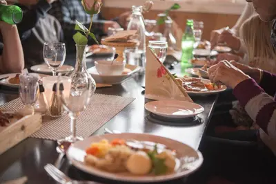 a group of people sitting at a table with plates of food at Hytter Dombås in Dombås