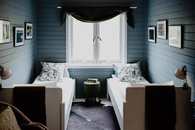 two beds in a blue room with a window at Fjærland Fjordstove Hotell - Huseby Hotelldrift AS in Fjarland