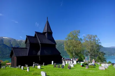 a black church with a bunch of graves in front at Vassbakken Kro og Camping in Skjolden