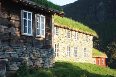 a stone building with a grass roof on a hill at Vassbakken Kro og Camping in Skjolden
