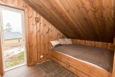a bed in a wooden room with a window at Trysilsetra 40 in Trysil