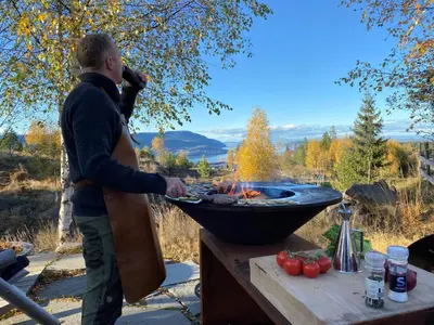 a man is cooking food in a grill at Konglehytta 1 - 30 min fra OSL - Badstu - Utsikt - Romantikk in Strandlykkja