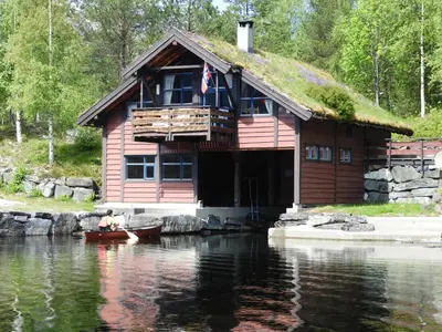 a log cabin with a grass roof on the water at Naustloftet in Hornindal