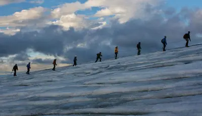 a group of people walking up a snow covered slope at Trolltunga Camping in Odda