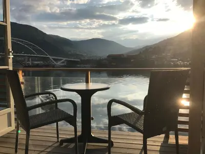 a table and chairs on a deck with a view of a bridge at Loftesnes in Sogndal