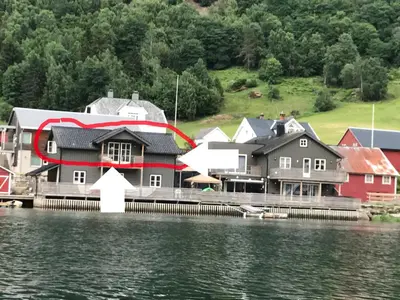 a house on a dock next to a body of water at Loftesnes in Sogndal